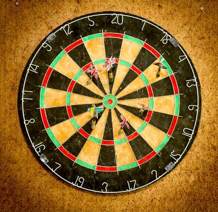 Darts on the dartboard hang on the wooden wall.の写真素材