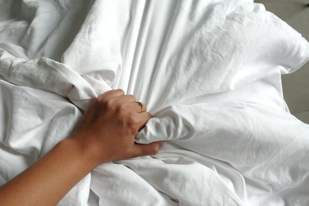 hand of women pulling white sheets in ecstasy, orgasm.の写真素材