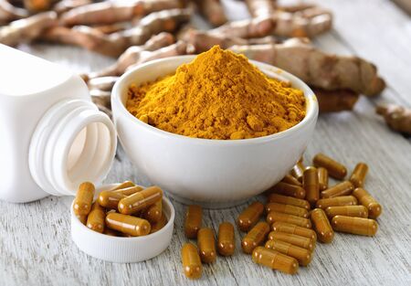Turmeric powder in white cup on wooden floor