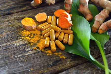 Turmeric powder and turmeric capsules on wooden backgroundの写真素材