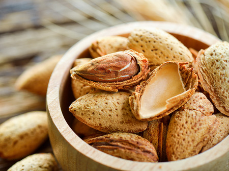 Almonds in a bowl on wooden background