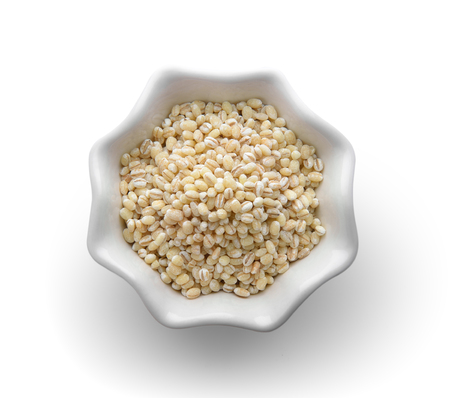 Heap of pearl barley in a bowl on white.の写真素材