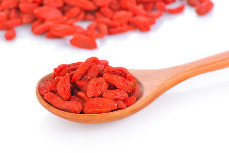 dried goji berries in wood spoon on white backgroundの写真素材