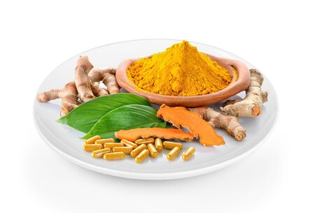 Turmeric powder and turmeric capsules in a plate on white backgroundの写真素材