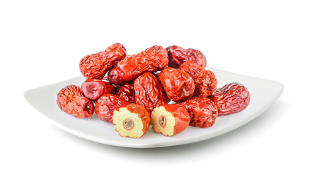 Dried red date or Chinese jujube in a plate isolated on white backgroundの写真素材