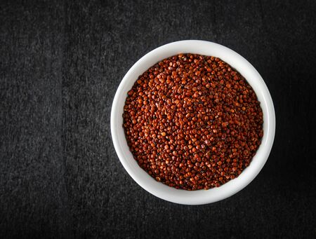 Quinoa in white bowl on blackwood. top viewの写真素材
