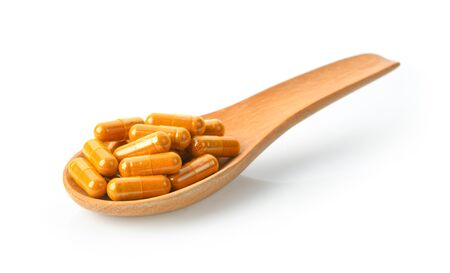 Turmeric Capsule in wood spoon on white backgroundの写真素材
