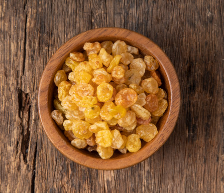 Raisins in a wooden bowl on a wooden backgroundの写真素材