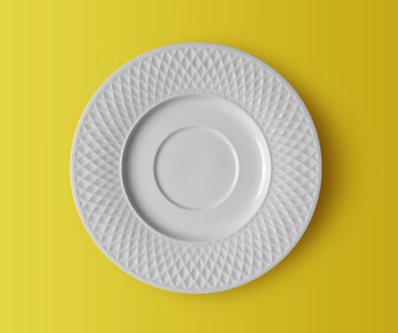 white ceramic plate on yellow backgroundの写真素材