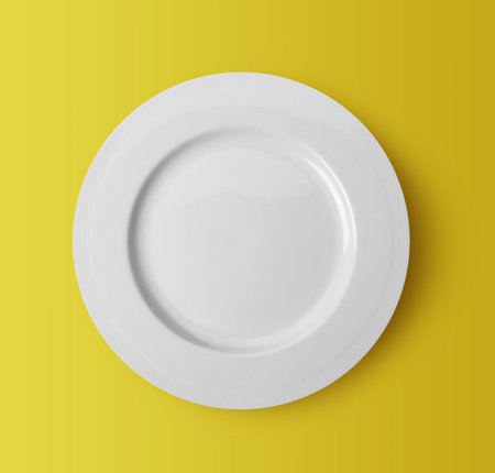 white ceramic plate on yellow backgroundの写真素材