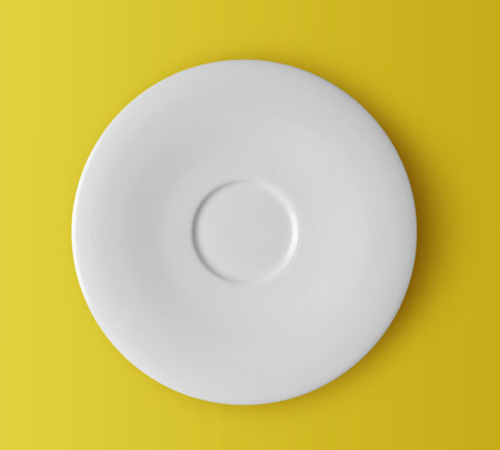 white ceramic plate on yellow backgroundの写真素材