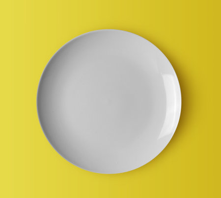 white ceramic plate on yellow backgroundの写真素材