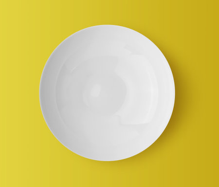 white ceramic plate on yellow backgroundの写真素材