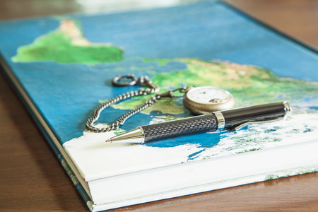 Map book, pens, pocket watch on wood tableの写真素材