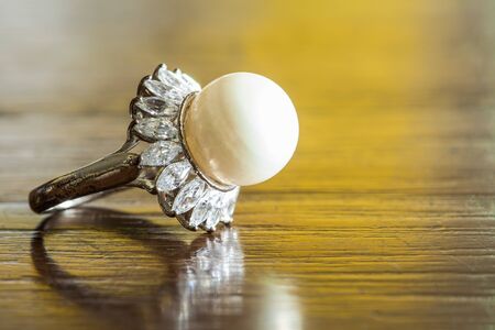 Old beautiful pearl ring on wood tableの写真素材