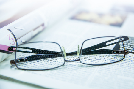 Photo of eyeglasses lie on the magazinesの写真素材