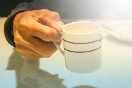Female hands holding coffee cup over dark tableの写真素材