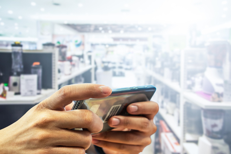 Smartphone in hands and Shopping Mall backgrounds