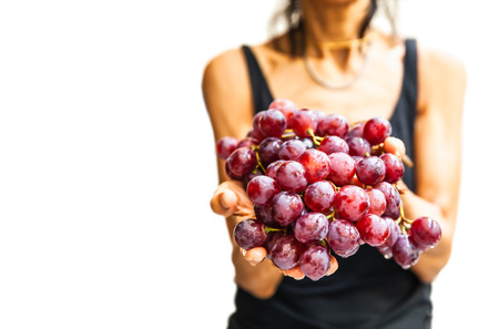 Woman hands with fresh red grapes isolated on whiteの写真素材