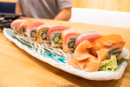 Salmon & tuna sushi roll on ceramic plate on wooden table in Japanese restaurantの写真素材