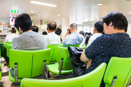 People sitting on chairs waiting in queue to wait for treatment from doctors in the Kluaynamthai Hospital at Rama 4 road Bangkok Thailand,  March 13, 2019のeditorial素材