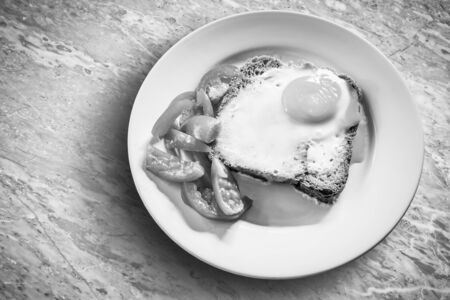 Cooked eggs by baking and whole wheat bread on a white plateの写真素材