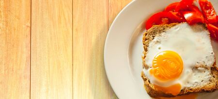 Cooked eggs by baking and whole wheat bread on a white plateの写真素材