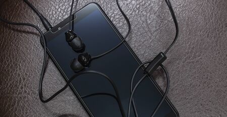 Smartphone and earphones placed on leather floor