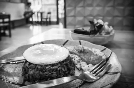 Fried eggs on brown rice and  baked chicken in plates with salad bowls on the table in Thai restaurantsの写真素材