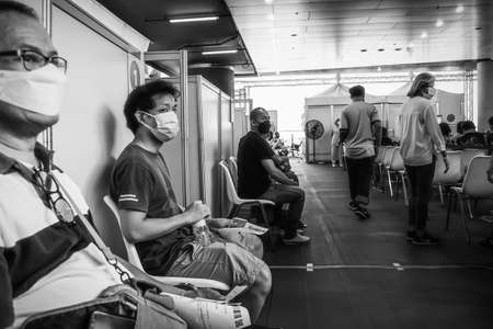 People sitting and waiting in queue for vaccinations to against covid 19 at vaccination center Sukhumvit road Bangkok Thailand, August 25, 2021のeditorial素材
