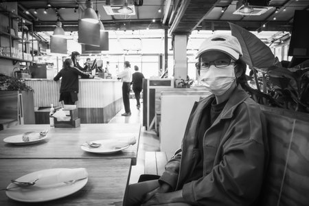 Woman wearing mask in a Thai restaurant waiting for food at soi Lasalle Sukhumvit road Bangkok Thailand, December 4, 2021のeditorial素材