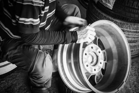 Man scrubbing alloy wheels before putting on new tires in a tire shopの写真素材