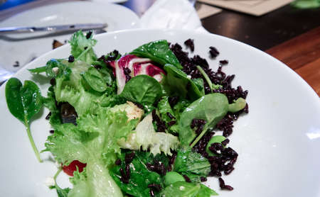Fresh salad in a white bowl on a table in restaurant
