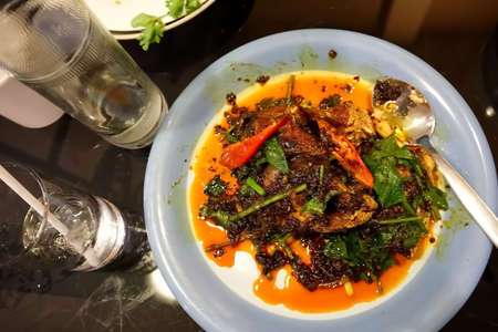 Fried fish with chili in plate on the tableの写真素材