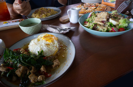 Rice with Basil Chicken and Fried Egg and all food on the table in restaurantの写真素材