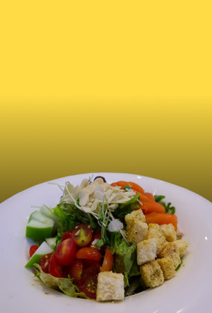 Salad on white plate isolated on yellow backgroundの写真素材