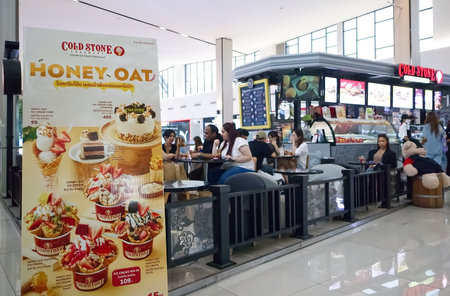 August 12, 2023, Signs display food items in front of ice cream and bakery shops and customers eat and drink inside the shop in a department store on Bangna-trad road Bangkok Thailのeditorial素材
