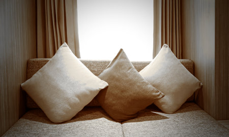 Beautiful three pillows on sofa interior decoration in living room with curtains and window, home related backgroundの写真素材