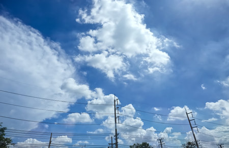 Electrical poles and wires against a sky with clouds, nature background