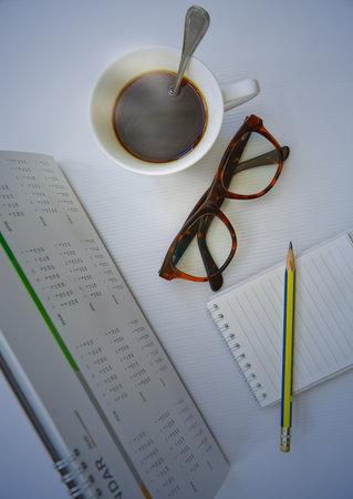 Desk calendar 12 months year 2025 with notepad eyeglasses pencil and hot coffee, object backgroundの写真素材