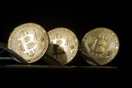 Three golden bitcoins with forks. Cryptocurrency concept