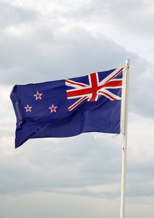 New Zealand flag on a blue sky with clouds backgroundの写真素材