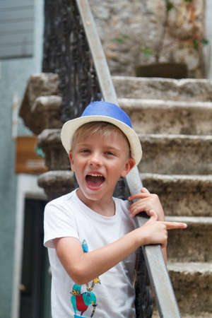 liitle kid in a blue hat, standing on the stairs of the ancient cityの写真素材