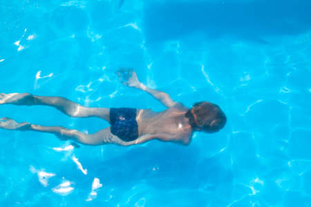 boy in a blue hat sitting on parapet of the ancient fortress of Old town in Budva, Montenegroの写真素材