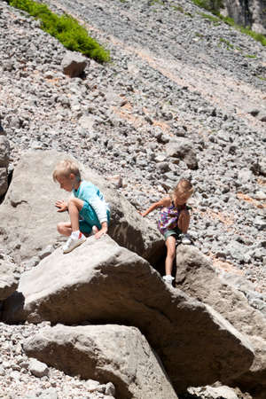 little girl sitting on a mountainside not far above is serene her brotherの写真素材