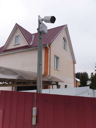 Surveillance and safety home concept. Security CCTV camera monitoring perimeter of private house in...
