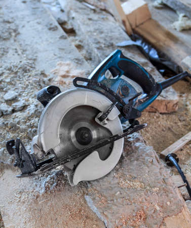 manual circular saw is on a wooden board in house under construction of foam block