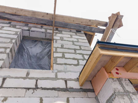 close up view of scaffolding and house under construction with gray folding roof on waterproofing...