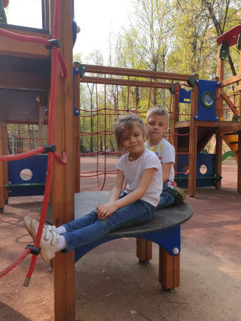 happy boy and girl standing on the Playground in the spring and looking at the camera
