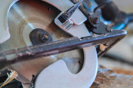 close up view of manual circular saw is on wooden boardの写真素材